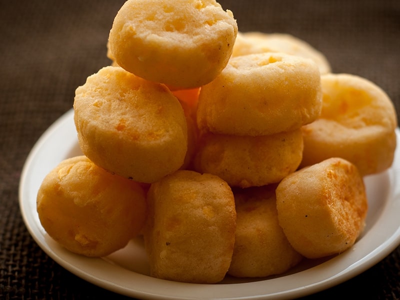 Prato de chipa, um tradicional pão de queijo paraguaio, disposto em uma pilha sobre um prato branco, destacando a textura dourada e crocante.