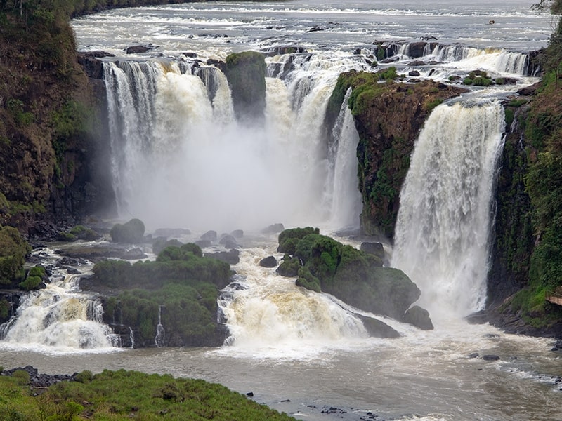 Vista deslumbrante das Cataratas do Iguaçu, com várias quedas d'água poderosas cercadas por vegetação exuberante, formando um cenário natural impressionante.